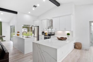 A modern kitchen with white cabinetry, a marble island, and stainless steel appliances. - Naples Pool Home 10 Min to Naples Zoo (Naples)