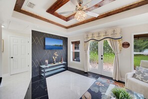 A spacious living room with a large flat-screen TV, a ceiling fan, and a view of the outdoors through a glass door. - Oldsmar Escape Near Tampa Bay Safety Harbor (Oldsmar)
