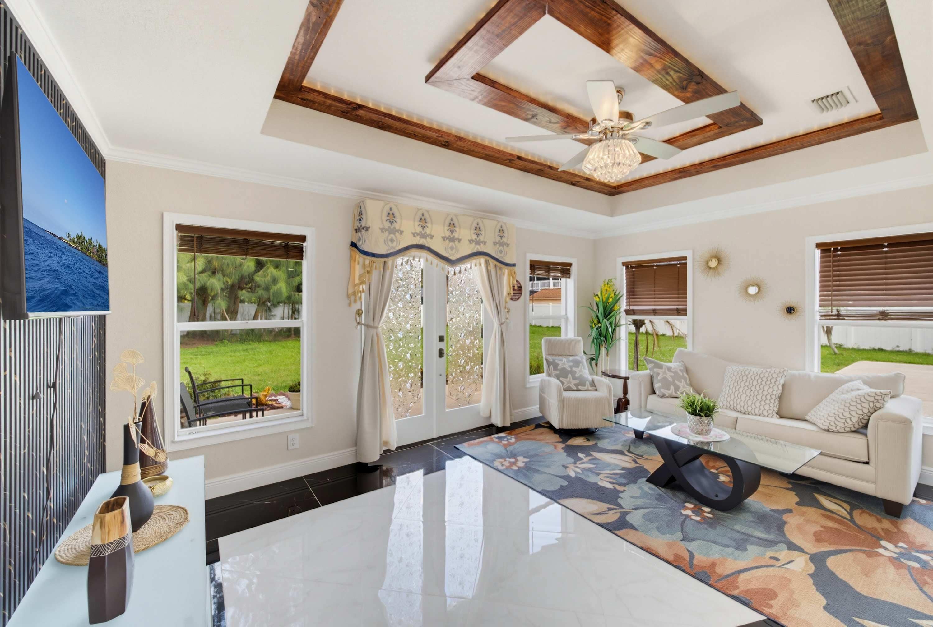 A spacious living room with a large window, a ceiling fan, and a view of the outdoors.
