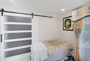 Ein Schlafzimmer mit einem Bett, einer Schiebetür, einem gerahmten Bild und einem Vorhang.