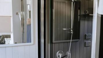 Ein Badezimmer mit einer Duschkabine, einem weißen Waschbecken und einem Spiegel.