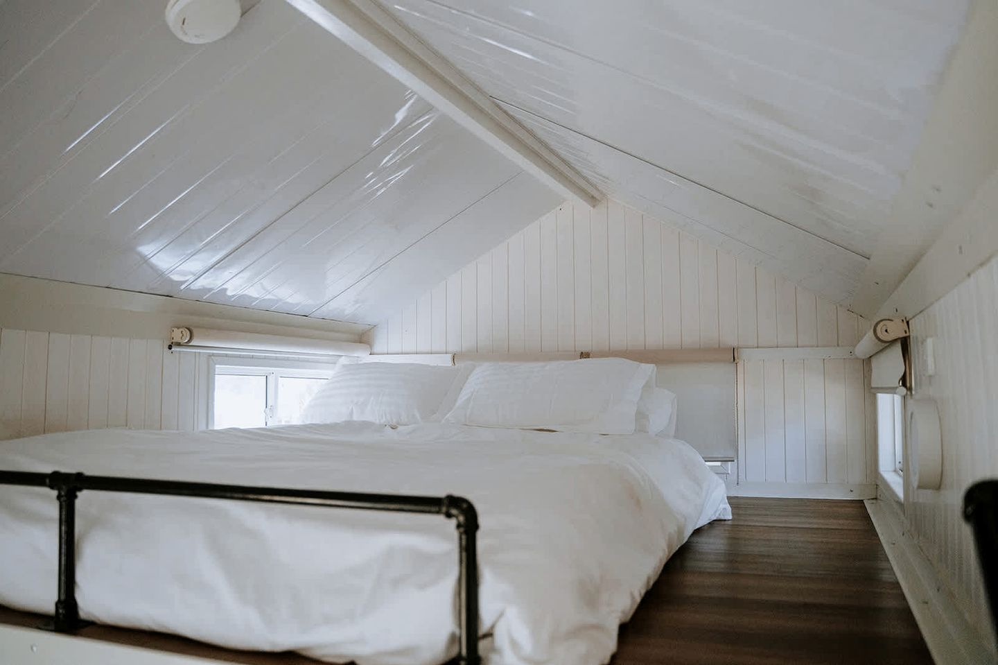 A room with a bunk bed, wooden walls, a window, and a skylight.