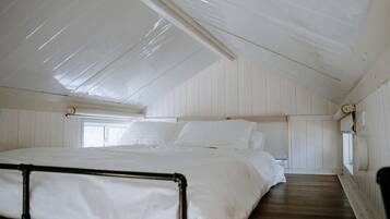 A room with a bunk bed, wooden walls, a window, and a skylight.