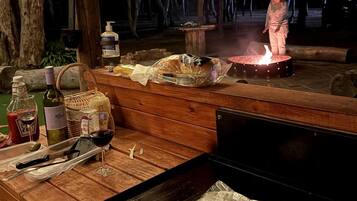 An outdoor barbecue setup with a grill, food items, and a fire pit.