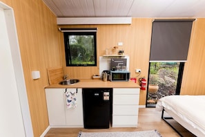 A compact kitchen with a sink, microwave, and a window with a view of greenery.