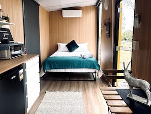 Une chambre compacte comprenant un lit, une petite kitchenette et donnant sur l’extérieur.
