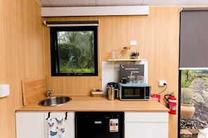 A compact kitchen with a sink, a microwave, a coffee maker, and a small refrigerator.