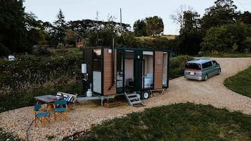 A mobile home with a small patio area, a table with chairs, and a van parked nearby.