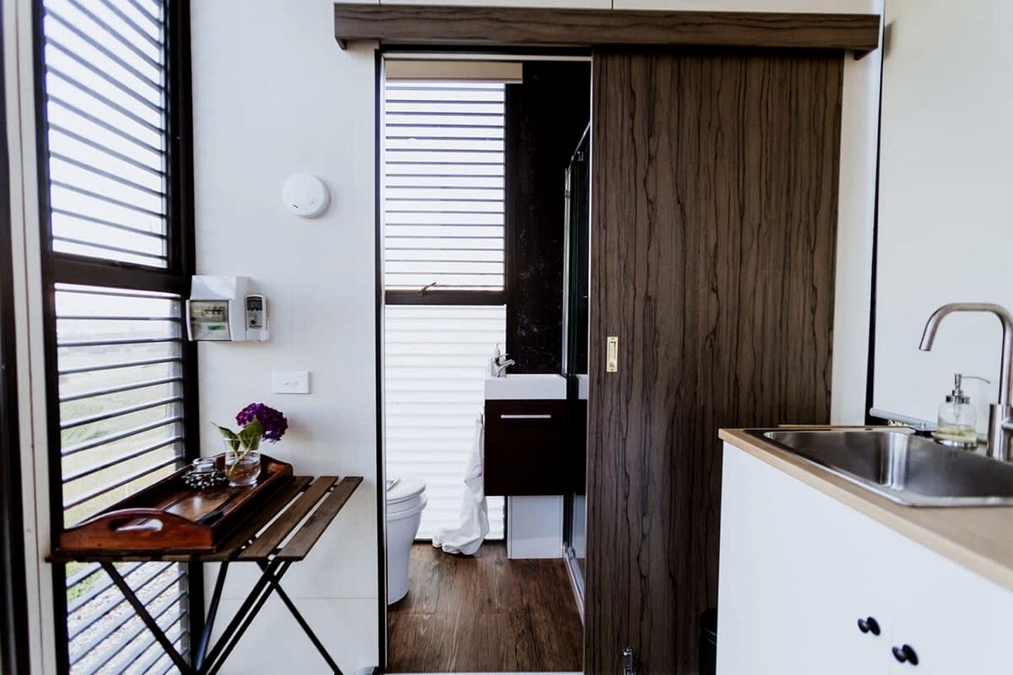 A compact kitchen with a wooden countertop, a sink, and a window with blinds.