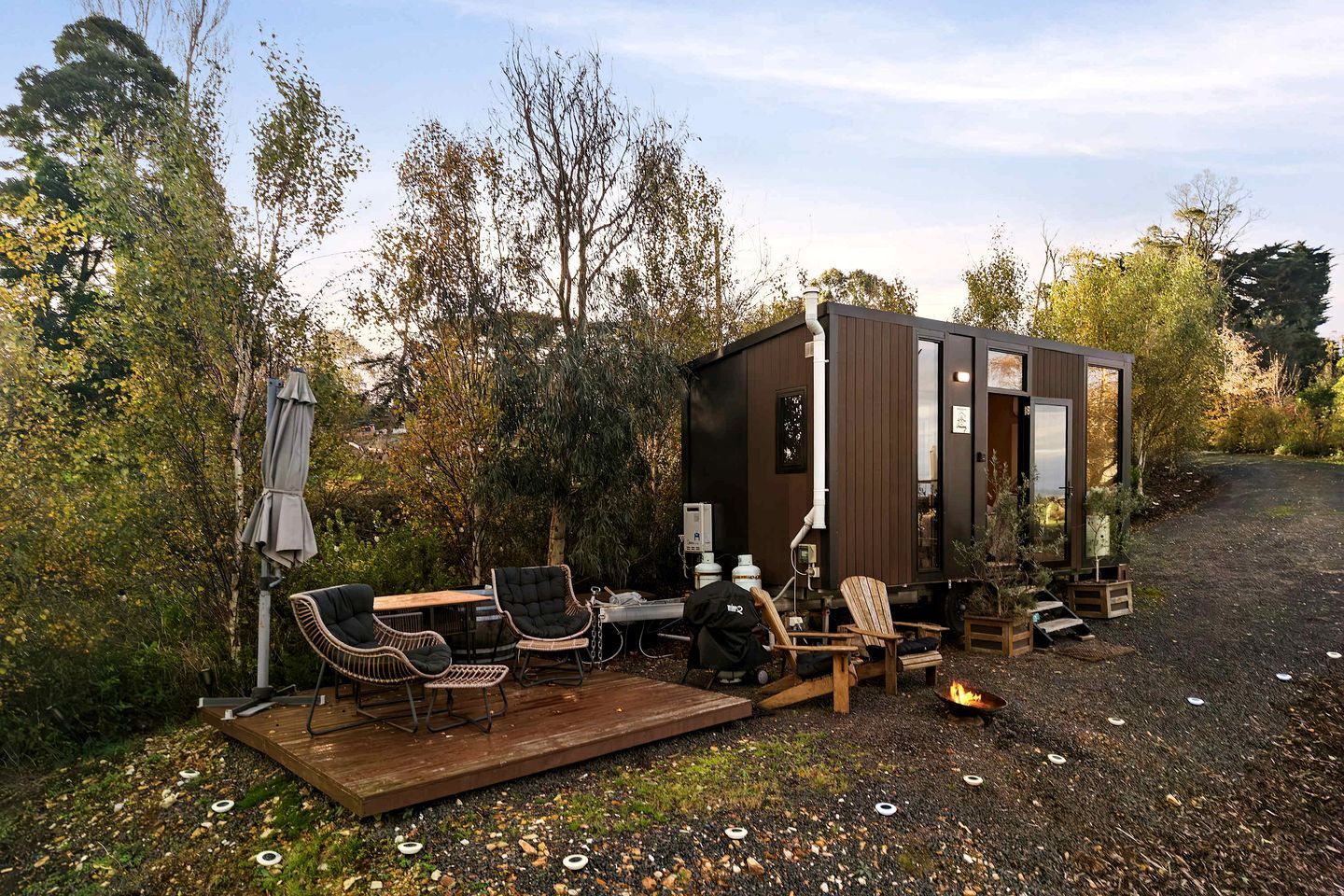 Une petite cabane dotée d’une terrasse, d’un espace salon extérieur et d’un foyer.
