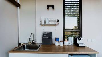 A kitchen with a wooden countertop, a sink, a chalkboard sign, and a window with blinds.
