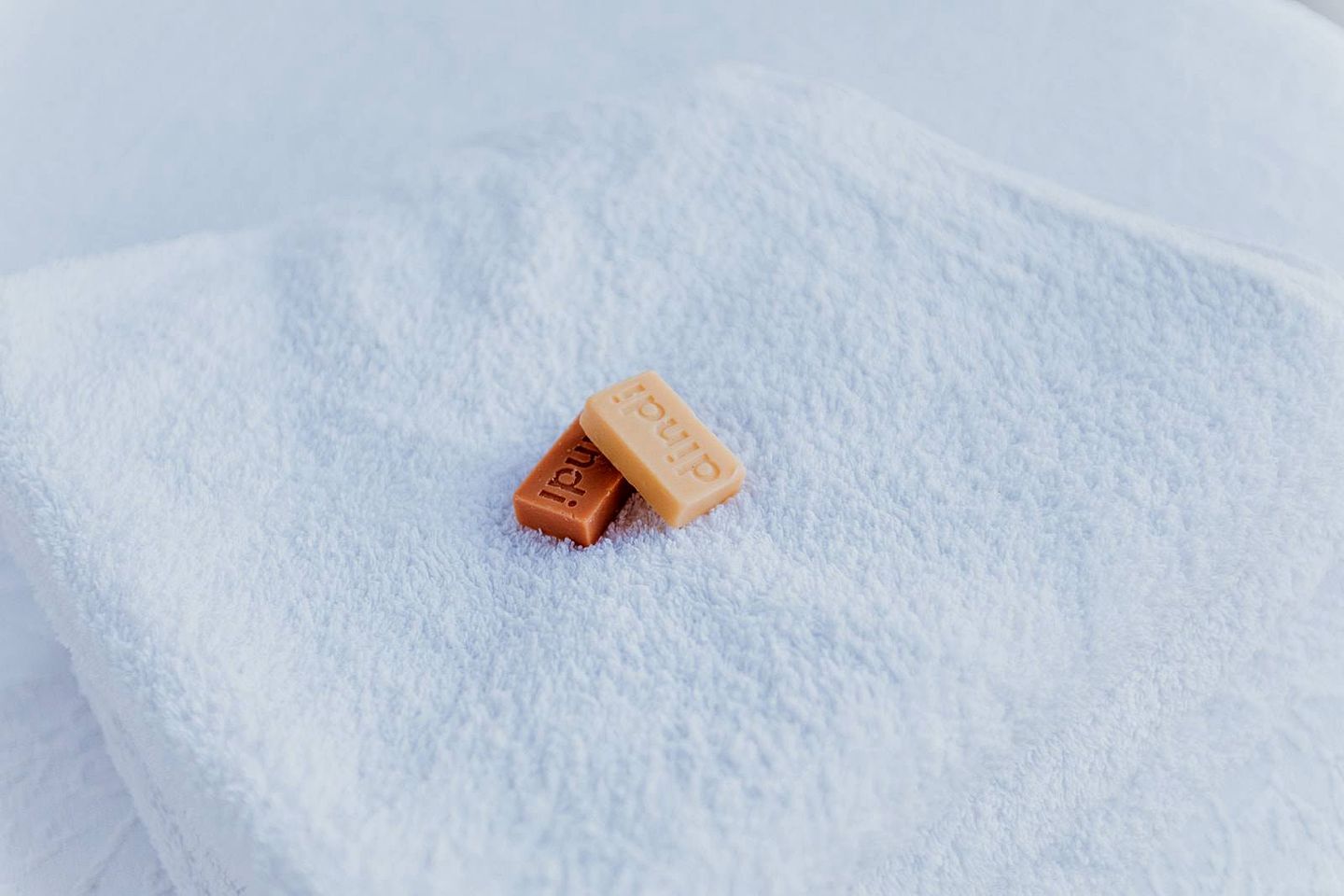 Two soap bars on a textured surface.