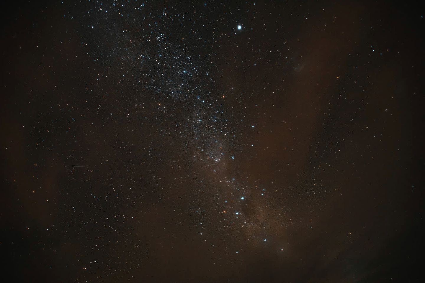 En stjärnklar natthimmel med synliga stjärnbilder och en svagt synlig galax.