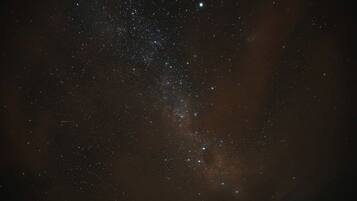 A starry night sky with visible constellations and a faintly visible galaxy.