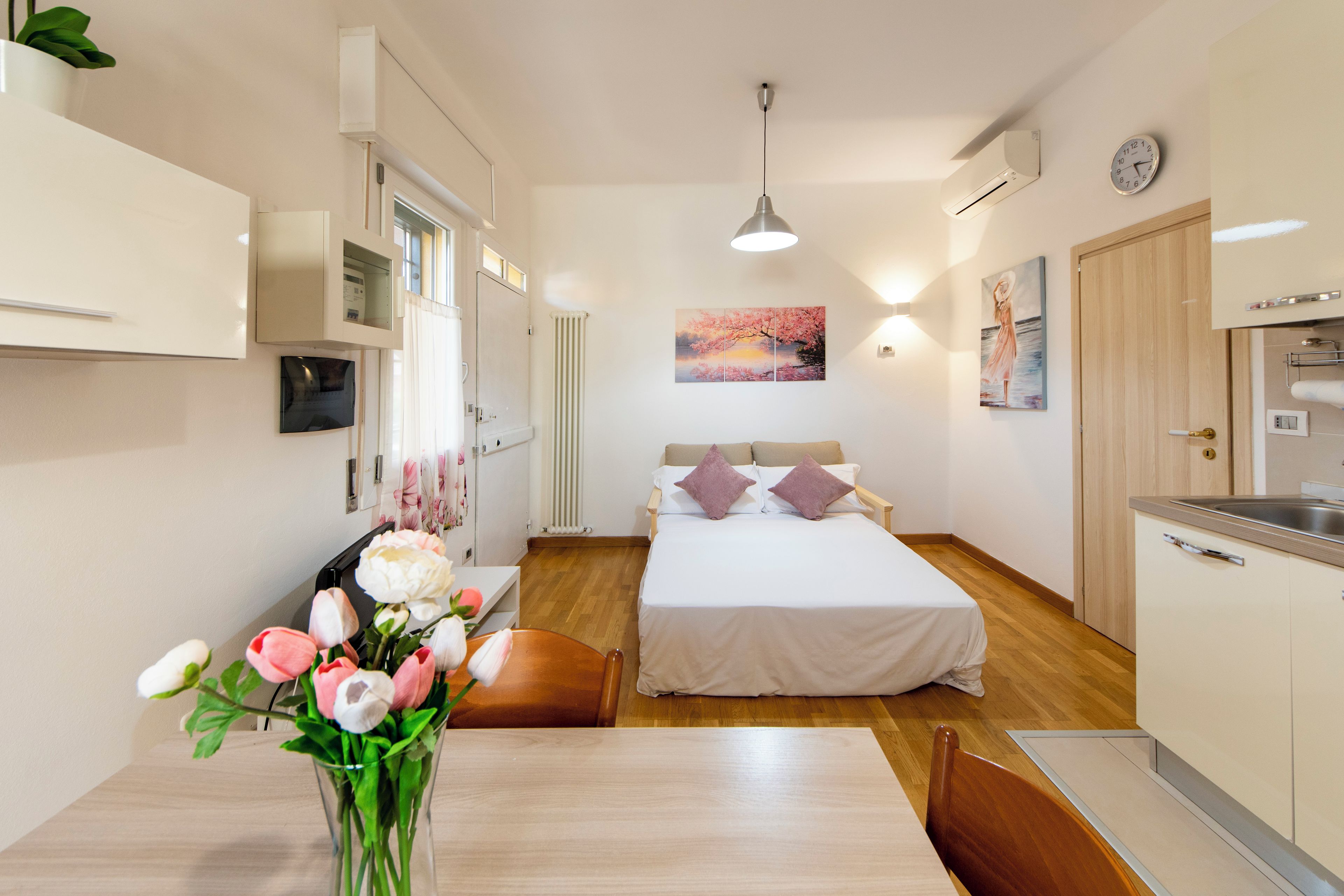 Ein modernes Schlafzimmer mit einem Bett, einem Nachttisch und einer Blumenvase.