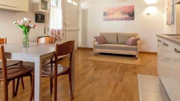 Eine moderne Küche mit Holzschränken, einem Esstisch mit Stühlen, einer Couch und einem Heizkörper.
