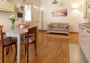 Et moderne køkken med træskabe, et spisebord med stole, en sofa og en radiator.