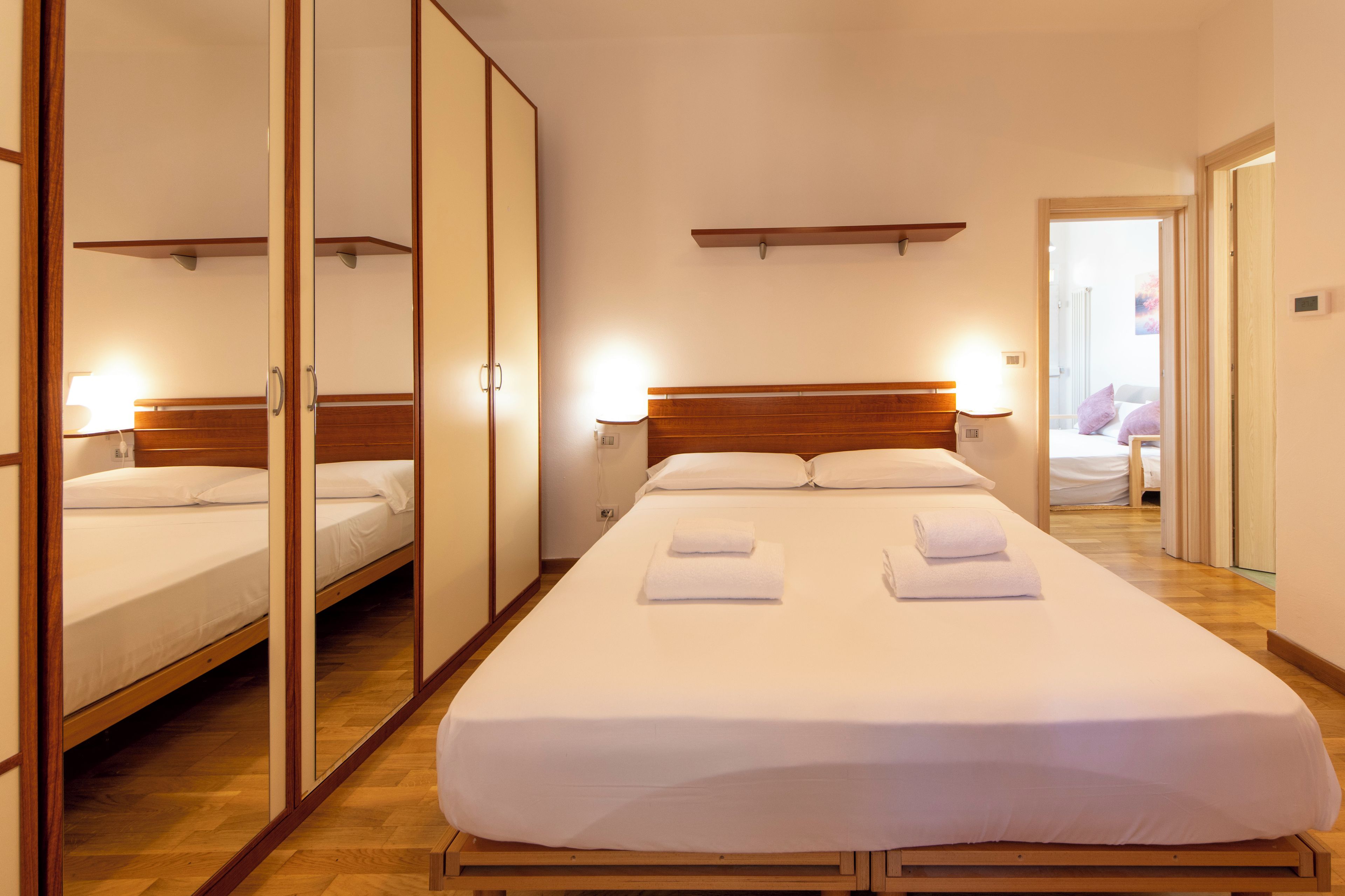 Une chambre d’hôtel avec un grand lit, une armoire et un miroir.