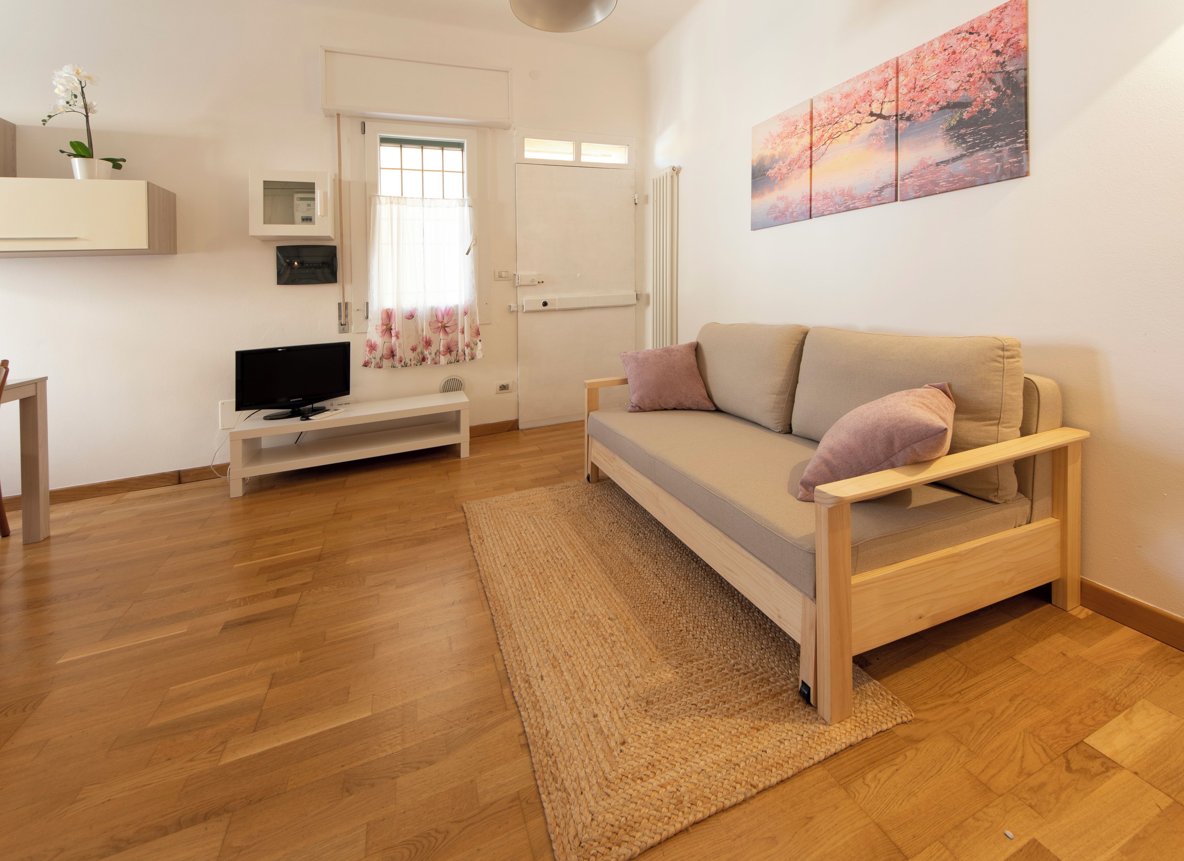 A modern living room with a sofa, a television, and a painting on the wall.