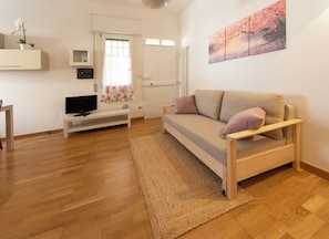 A modern living room with a sofa, a television, and a painting on the wall. - HouSmart Risorgimento 9 (Riale)