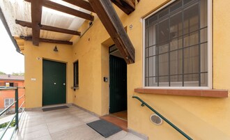 Un edificio con puerta verde, ventana con reja de metal y piso de baldosas.