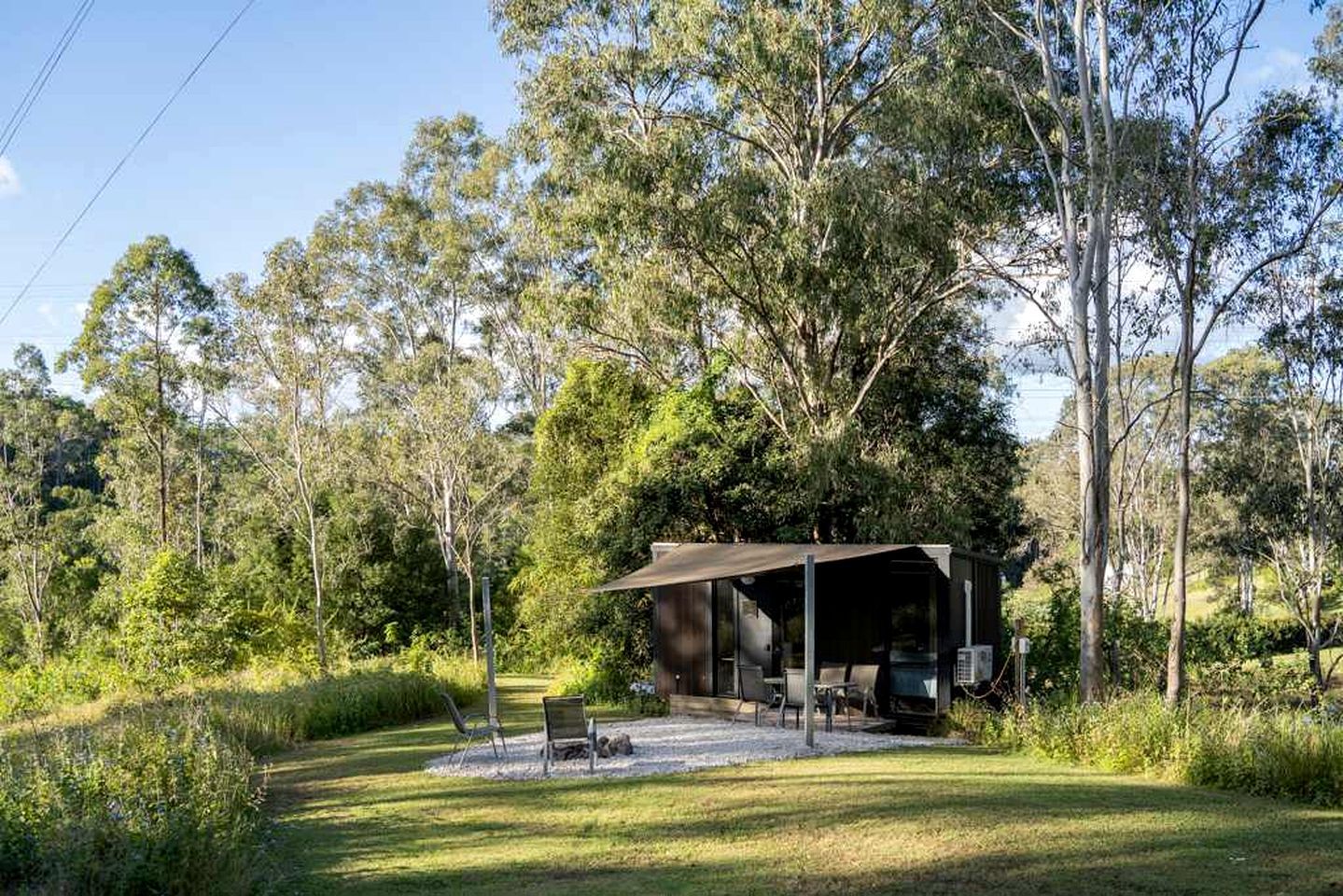 Un espace extérieur abrité, avec des chaises et une table, entouré d’arbres.