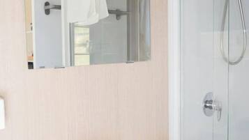 Une salle de bain avec un lavabo blanc, une cabine de douche en verre et un miroir au-dessus du lavabo.