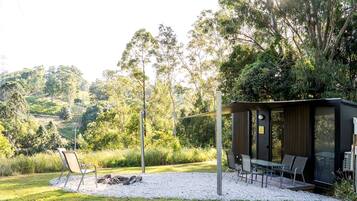A modern outdoor seating area with a table and chairs, surrounded by a gravel path and greenery.