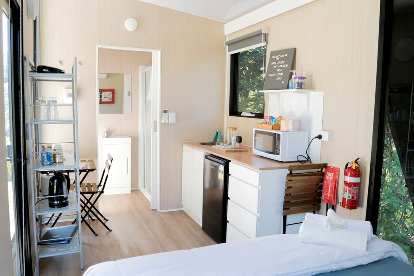 A compact hotel room with a kitchenette, a bed, a desk, and a chair.