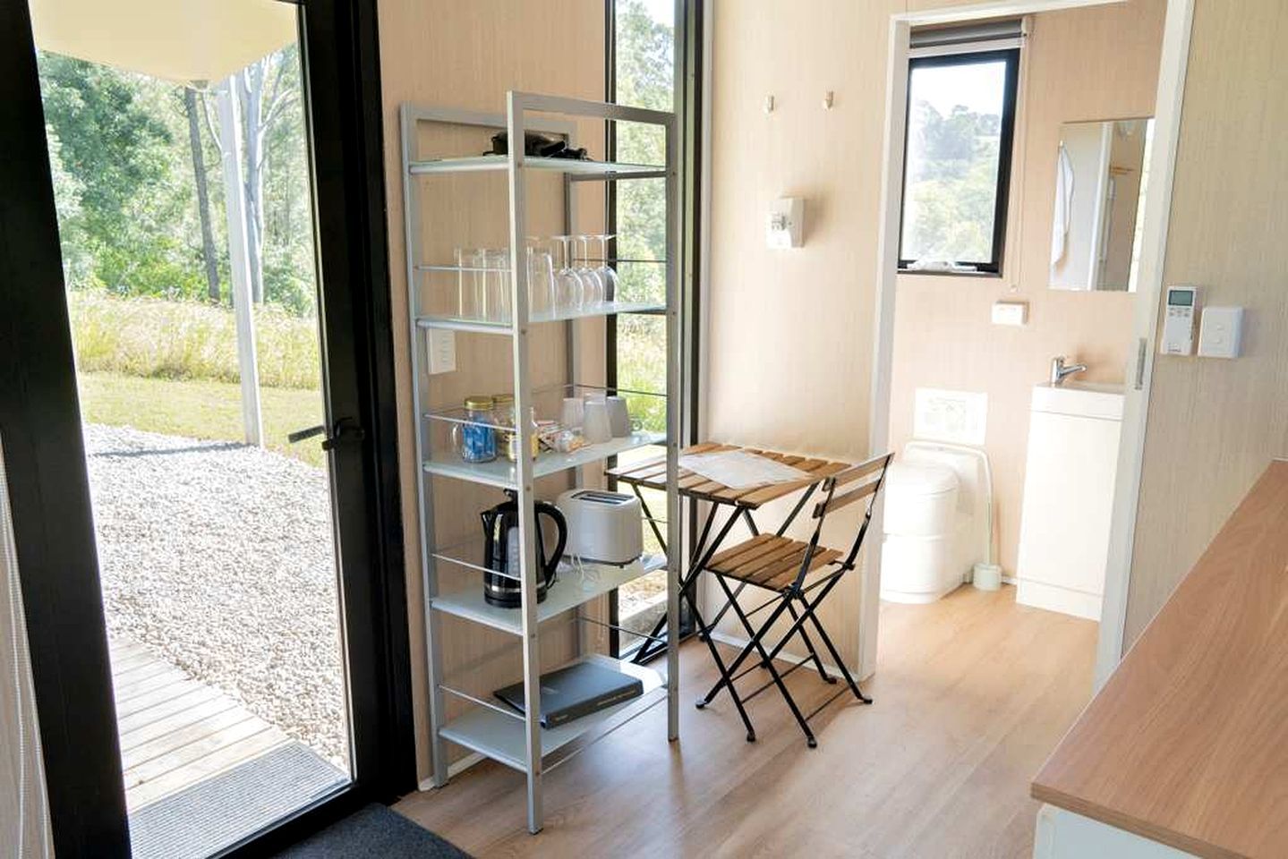 Una cucina compatta con un mobiletto a incasso, un tavolino e una finestra che offre vista sull'esterno.