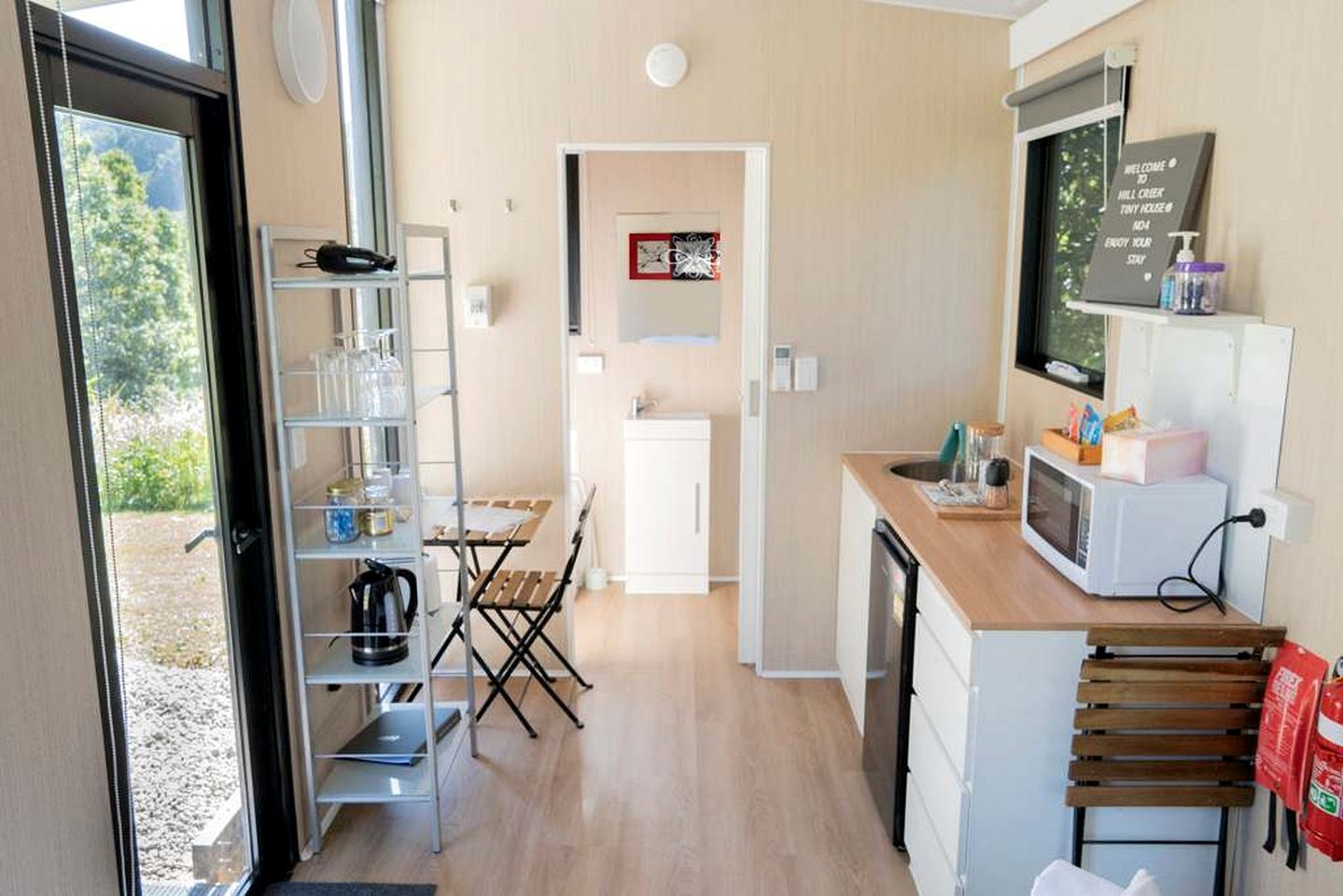 Une cuisine compacte équipée d’un four à micro-ondes, d’un petit réfrigérateur et d’une table en bois avec des chaises.