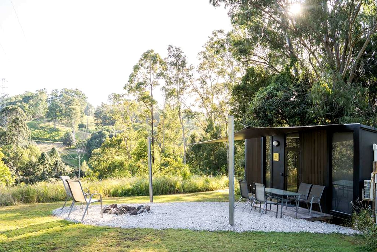 Un espace extérieur moderne aménagé avec une table et des chaises, entouré d’un chemin de gravier et de verdure.