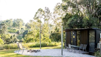 Un espace extérieur moderne aménagé avec une table et des chaises, entouré d’un chemin de gravier et de verdure.