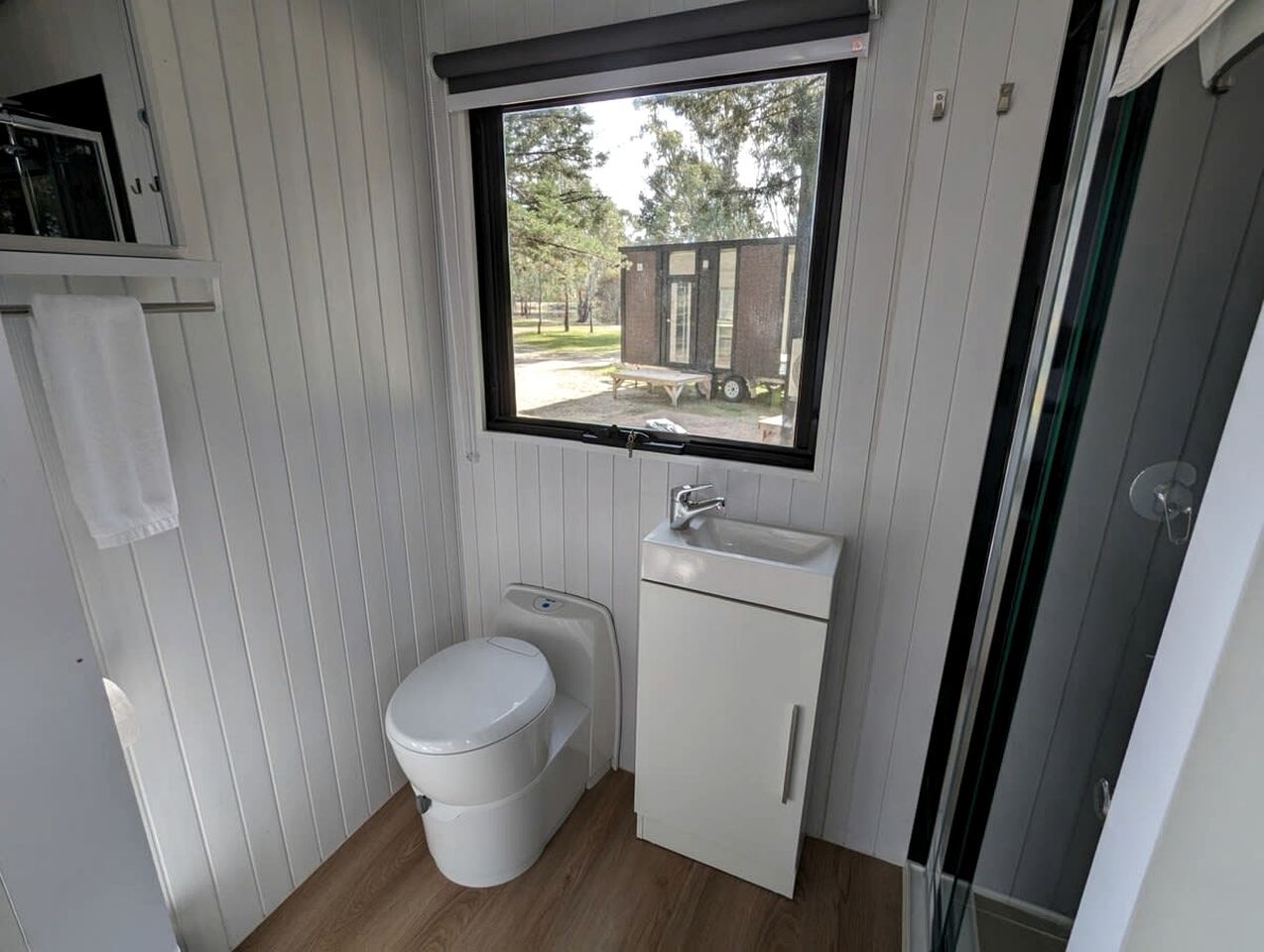 A compact bathroom with a toilet, sink, and a window providing a view of the outside.