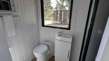 A compact bathroom with a toilet, sink, and a window providing a view of the outside.