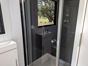 Une salle de bain moderne avec une paroi de verre, un lavabo et une fenêtre.
