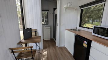 A compact kitchen with a wooden table, a black refrigerator, and a microwave on the counter.