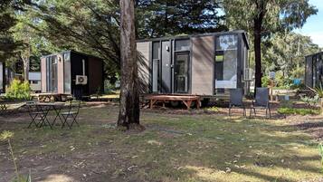 A campsite with portable cabins, a picnic table, and a tree.