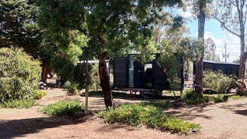 A campsite with RVs, trees, and a small building.