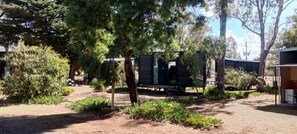 A campsite with RVs, trees, and a small building.