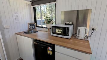 A compact kitchenette with a microwave, kettle, and sink.