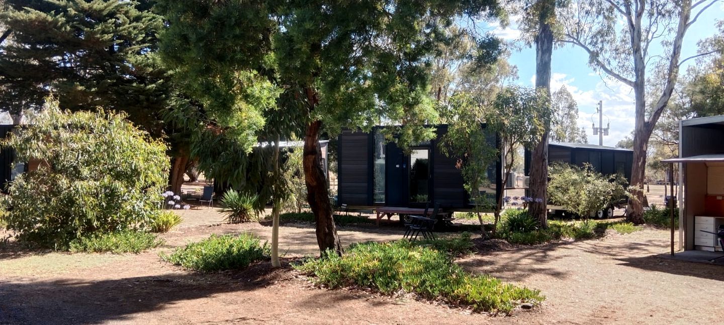 A campsite with RVs, trees, and a small building.