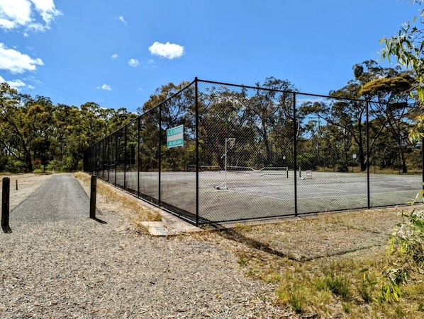 A fenced outdoor area with a gravel path leading to a parking lot.