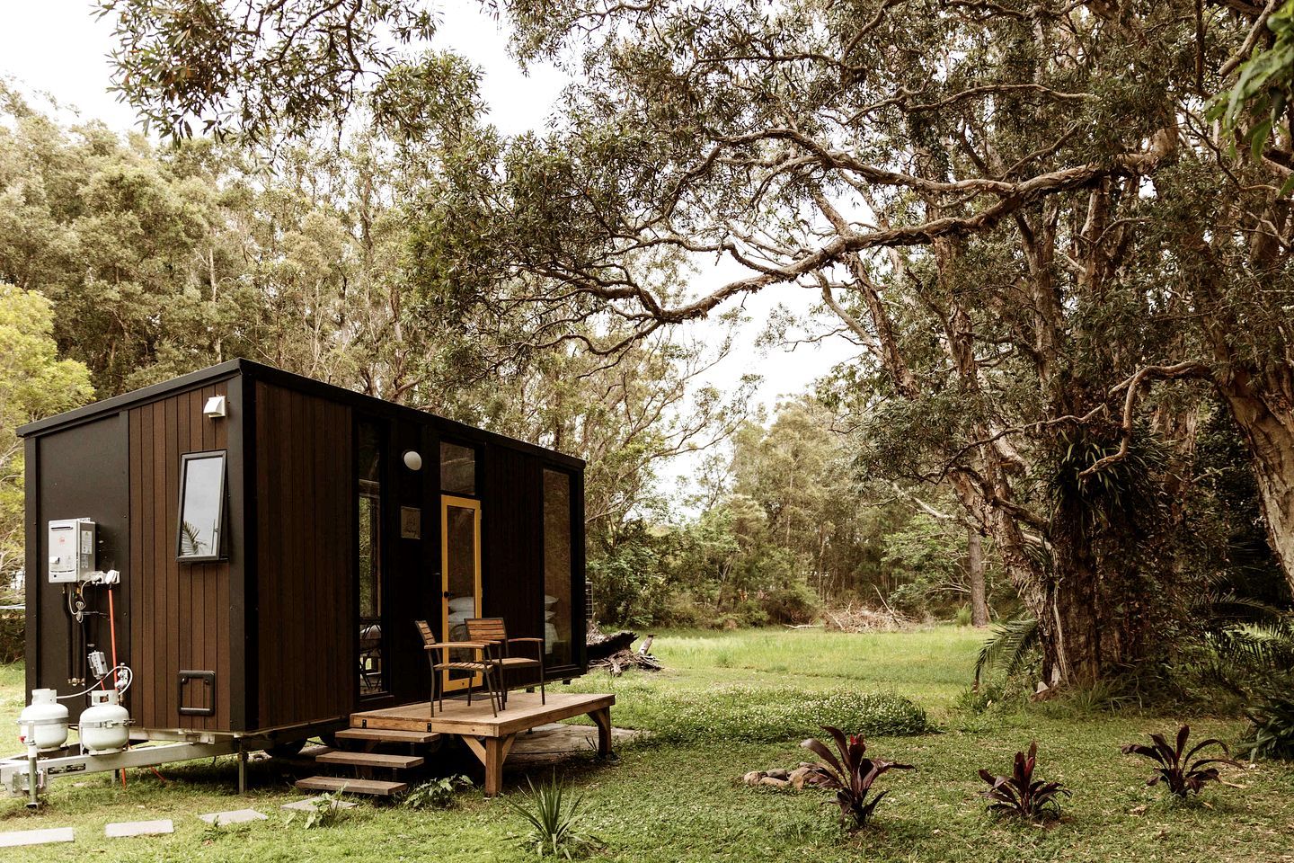 Uma cabana pequena com fachada de madeira, uma porta e um banco na parte externa.
