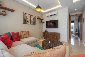 A modern living room with a sofa, a coffee table, a TV, and a fireplace. - Gauthier Nest, Top-Floor Luxury Apartment (Casablanca)