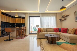 A modern living room with a sofa, coffee table, and dining area with chairs. - Gauthier Nest, Top-Floor Luxury Apartment (Casablanca)