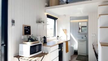 A compact kitchen with a microwave, coffee maker, and a welcome sign.