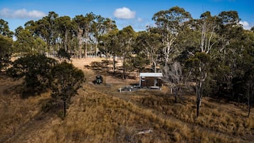 Un chalet isolé, entouré d’arbres, accessible par un sentier de terre.