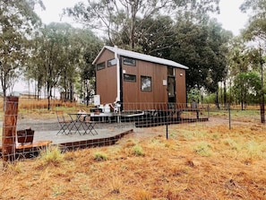 A wooden cabin with a fenced patio area, a small table, and chairs.