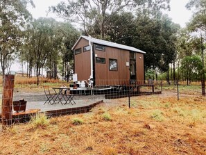 A wooden cabin with a fenced patio area, a small table, and chairs.